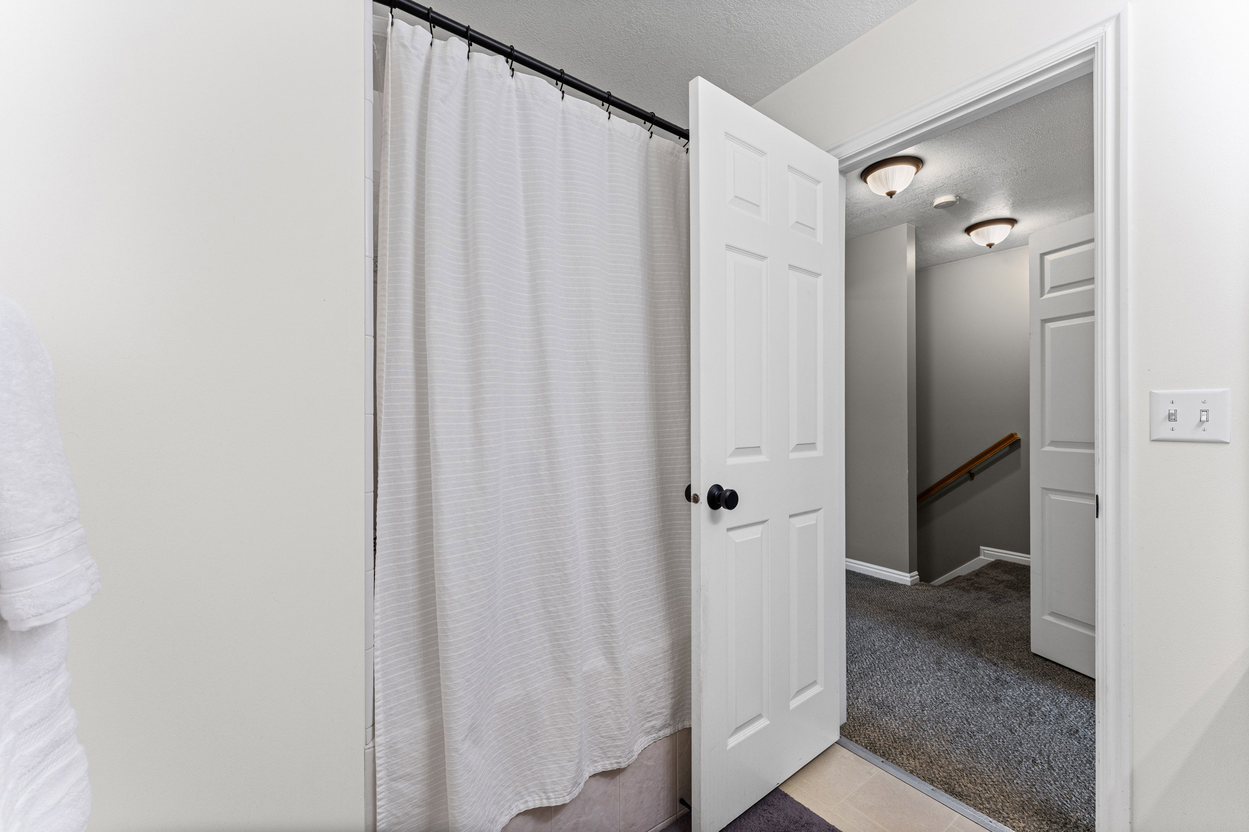 Bathroom featuring a shower with a white curtain, white paneled door with black hardware, and light-colored walls