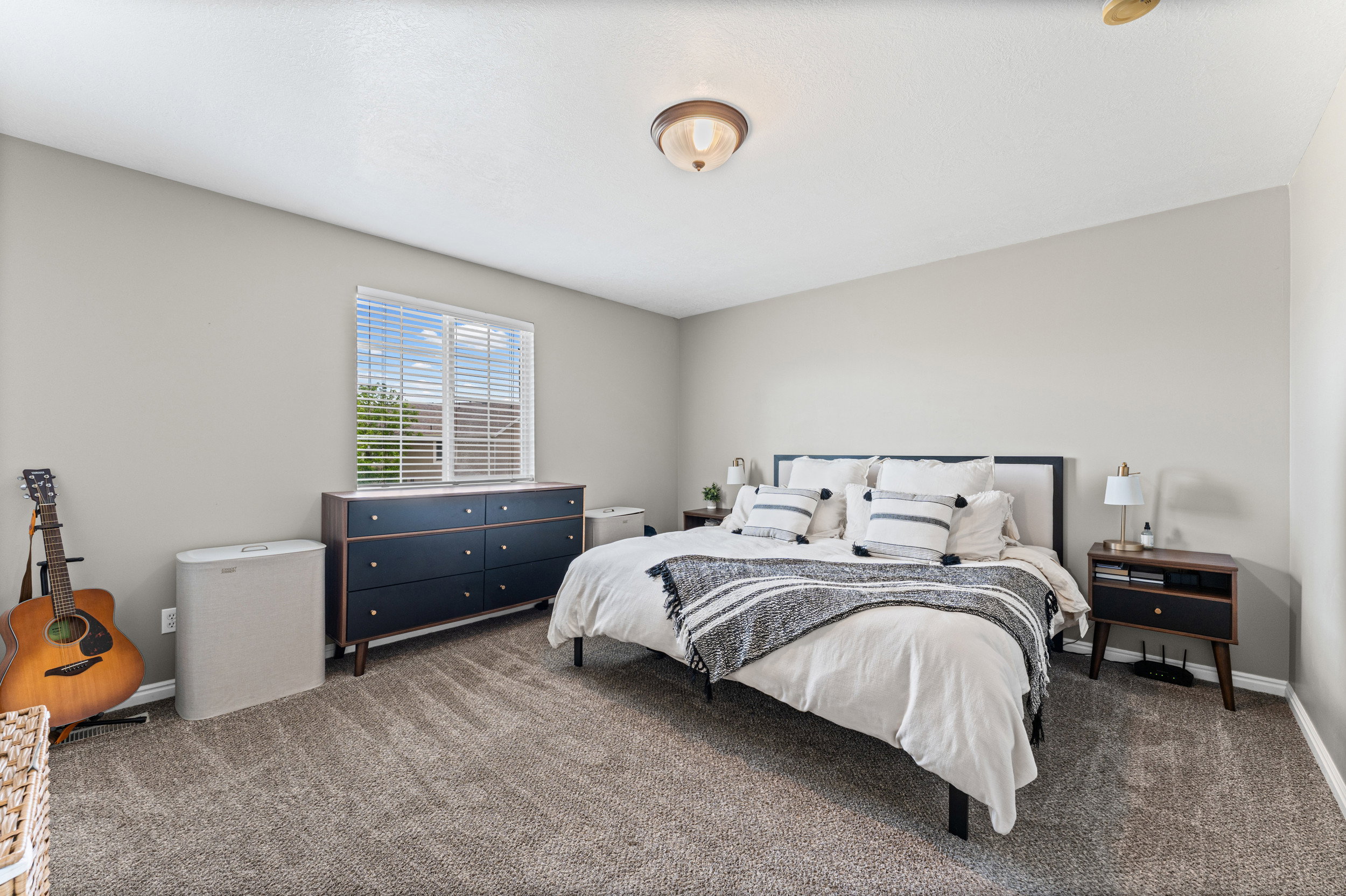 Carpeted bedroom featuring a flush mount ceiling light fixture, a window with blinds, and light gray wall paint