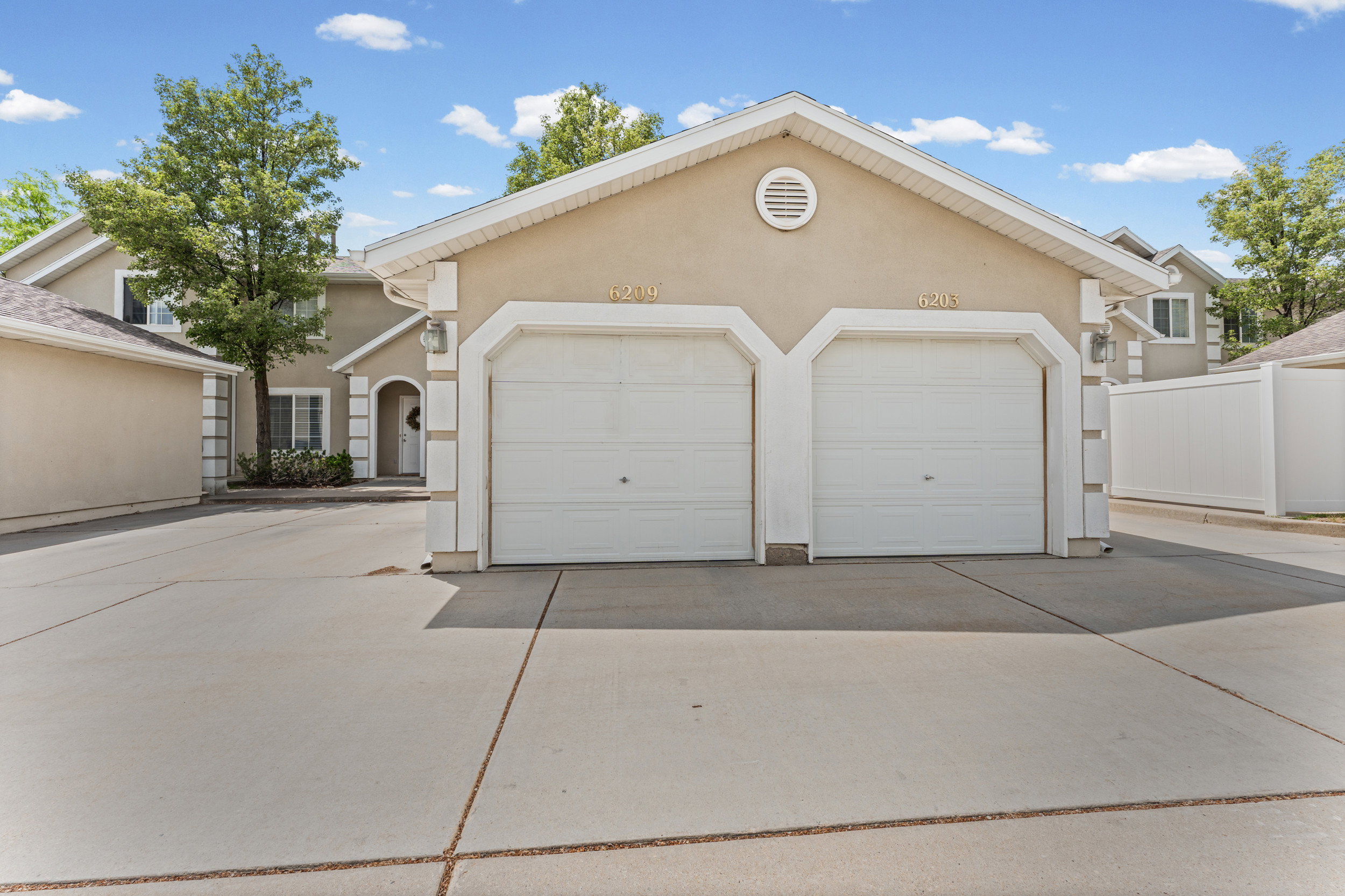 Stucco exterior with a two-car attached garage, white garage doors, and a concrete driveway