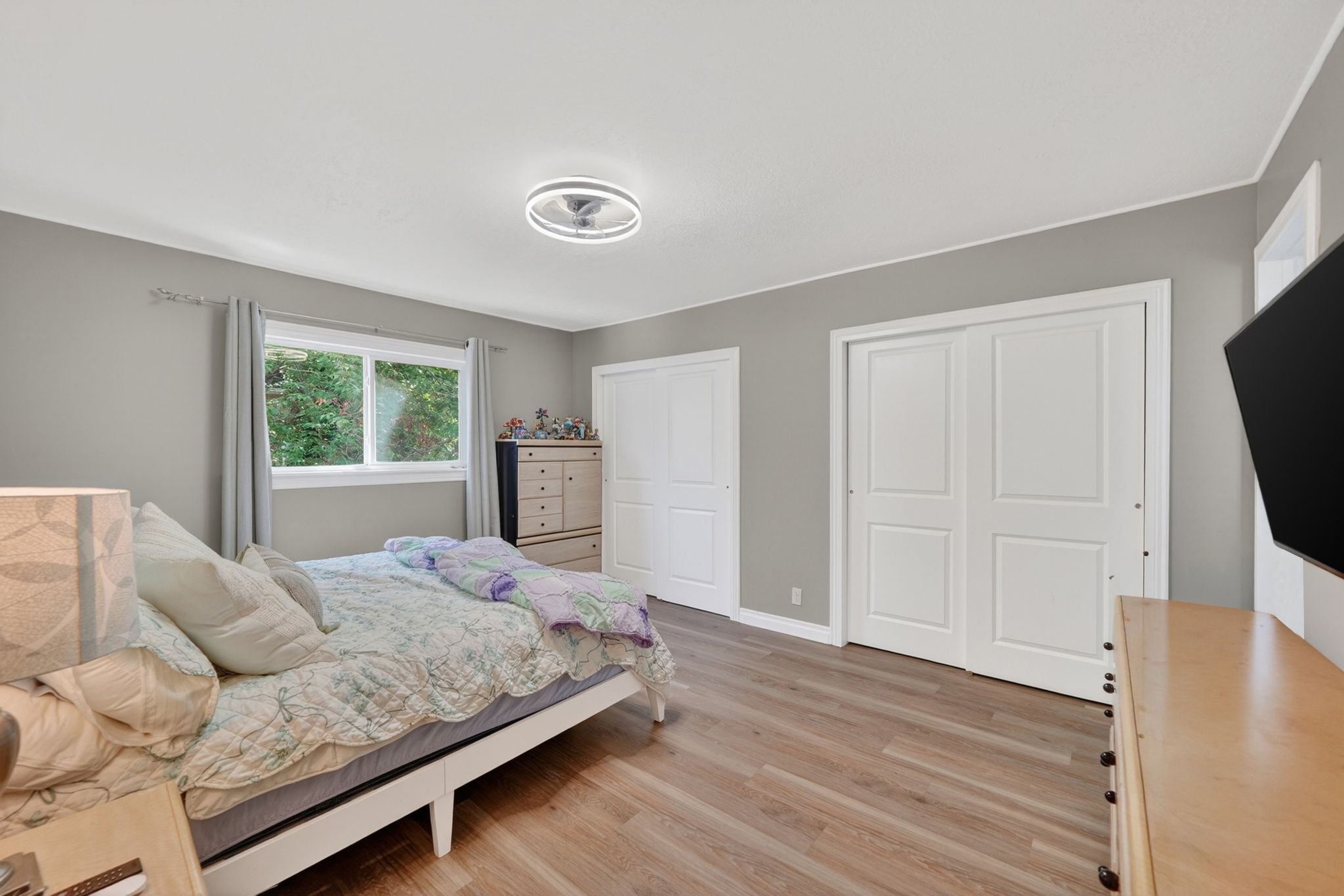 Bedroom featuring wood-finish flooring, a double window, and two sets of bi-fold closet doors