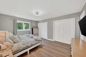 Bedroom featuring wood-finish flooring, a double window, and two sets of bi-fold closet doors