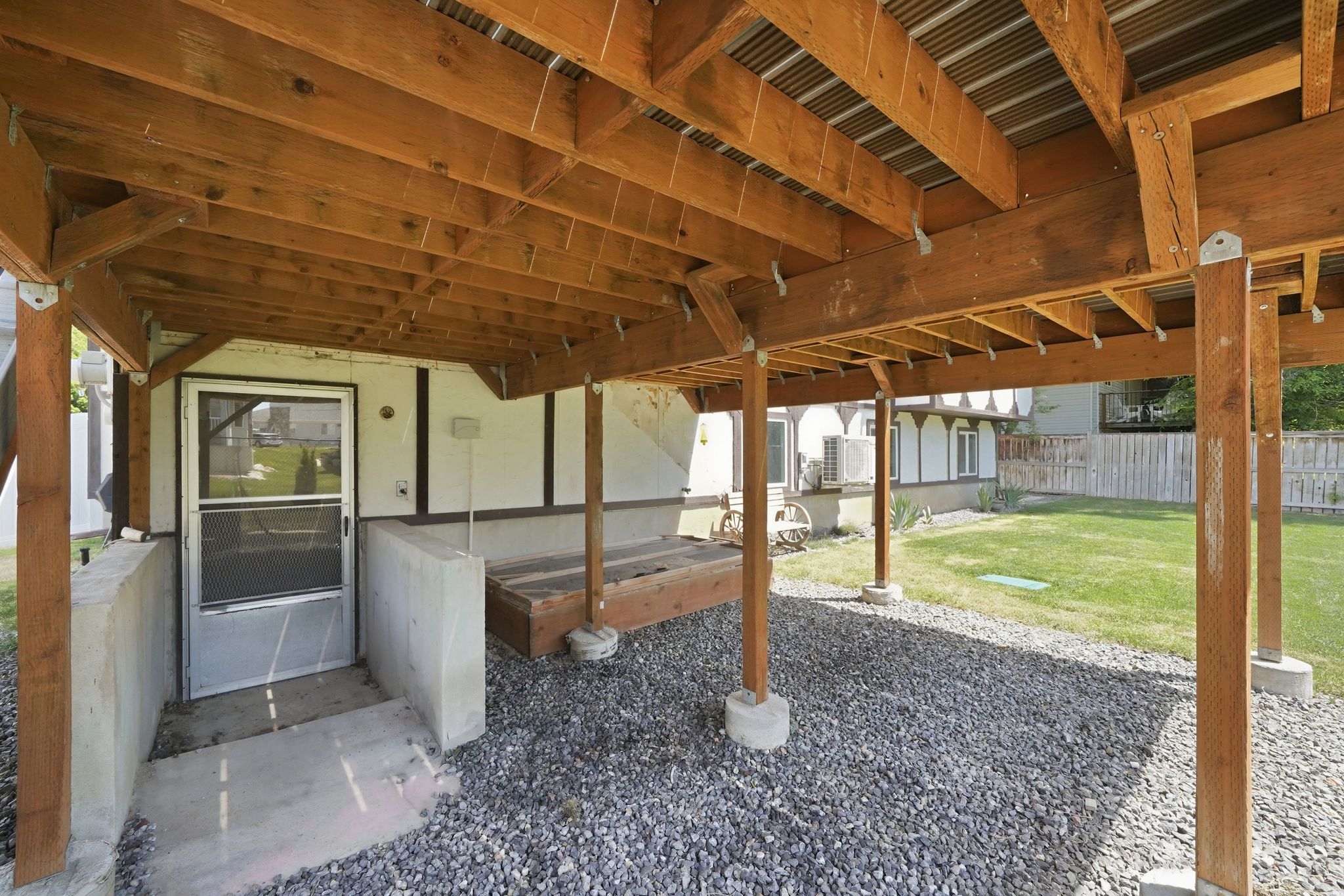 Covered outdoor space featuring a corrugated metal ceiling and exposed wood beams