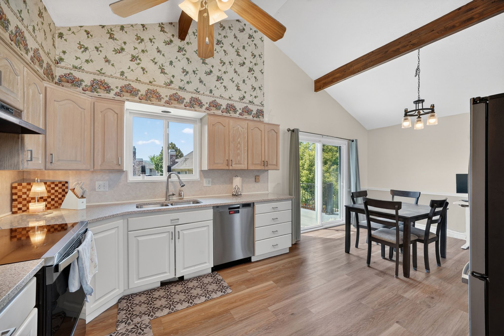 Kitchen and dining area featuring wood-finish flooring, vaulted ceilings with an exposed wood beam, and a ceiling fan