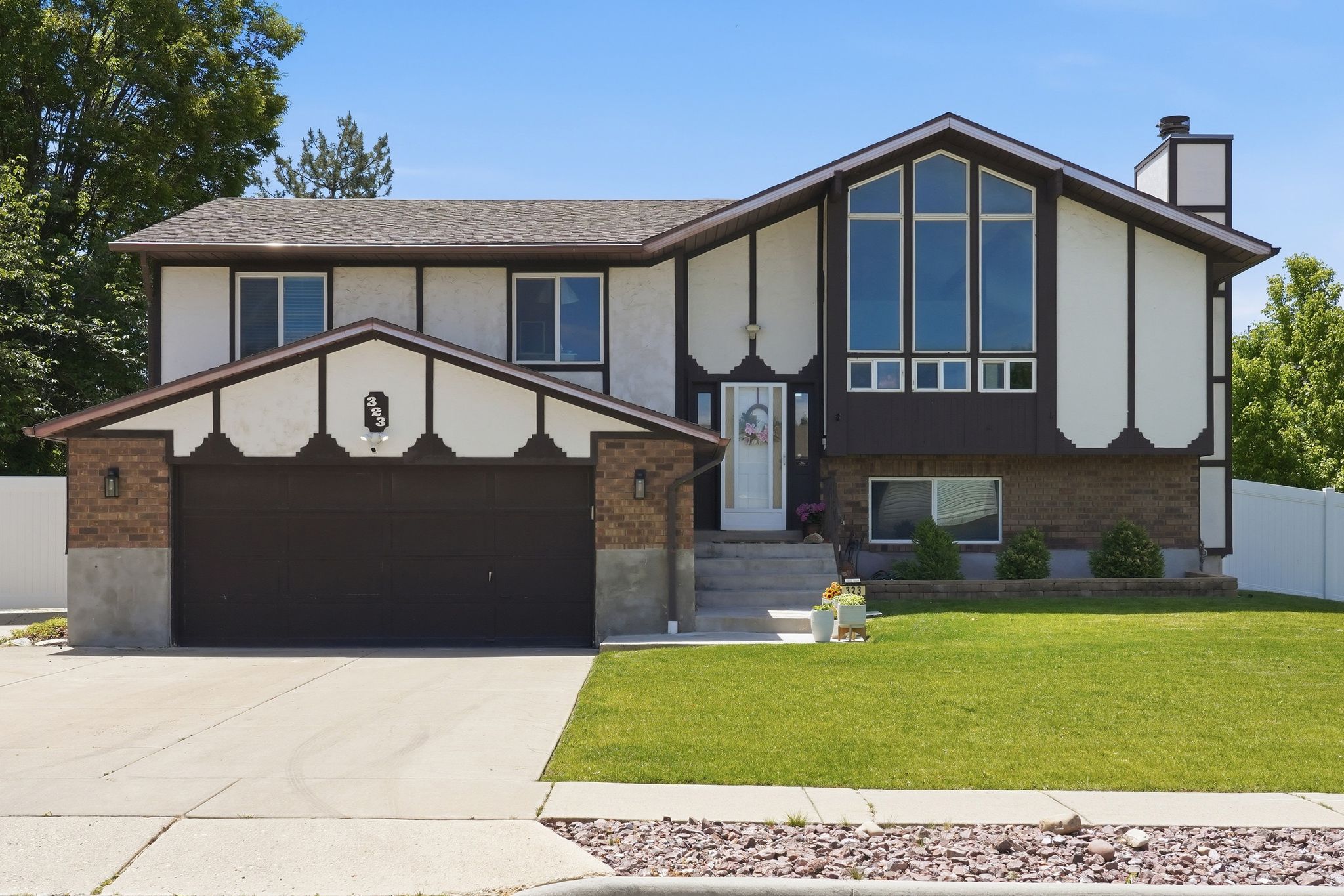Split-level residence featuring a prominent front gable with large windows, an integrated two-car garage, and a brick facade accent