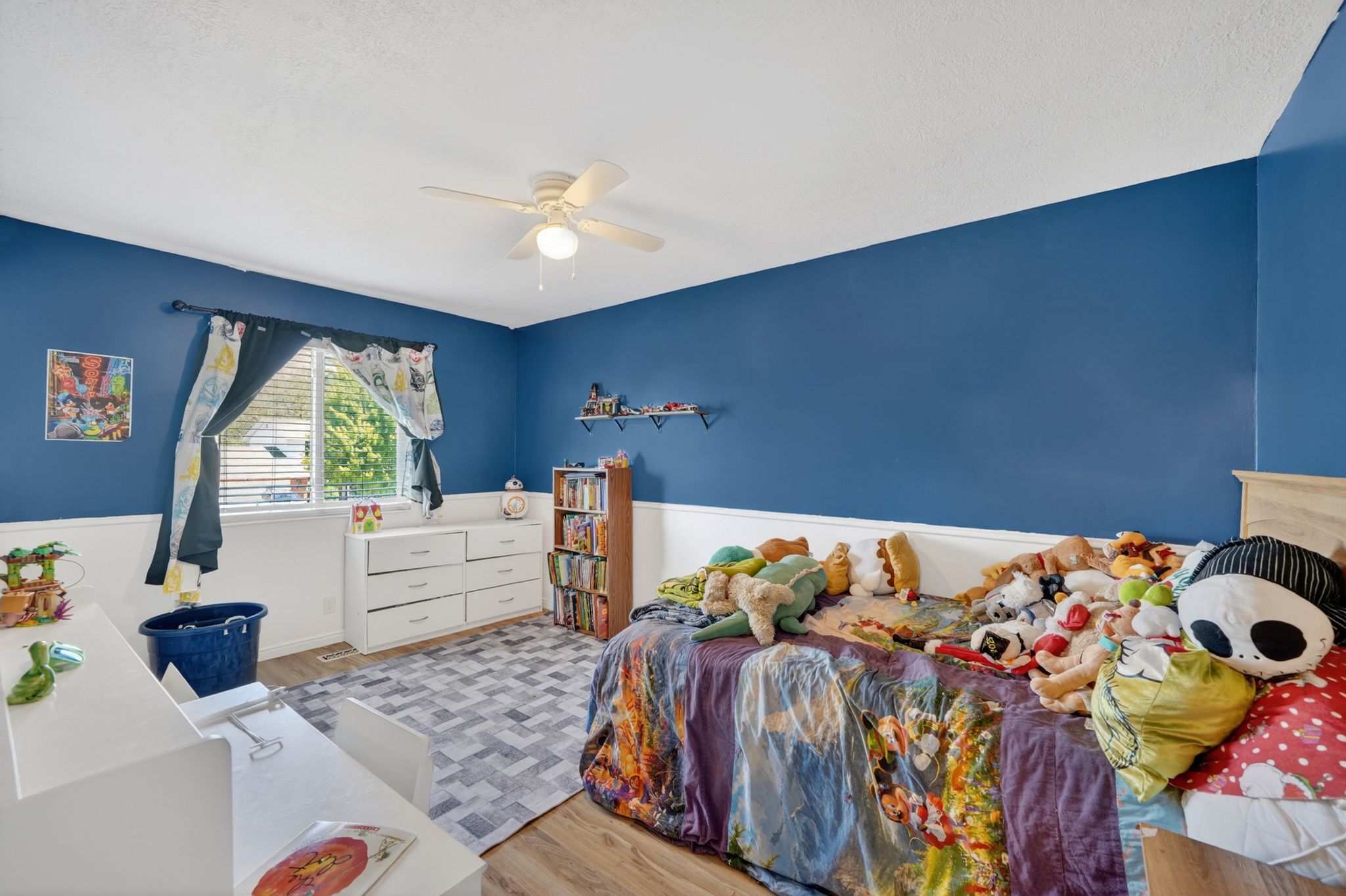 Bedroom featuring wood-finish flooring, a ceiling fan with integrated lighting, and a window with blinds