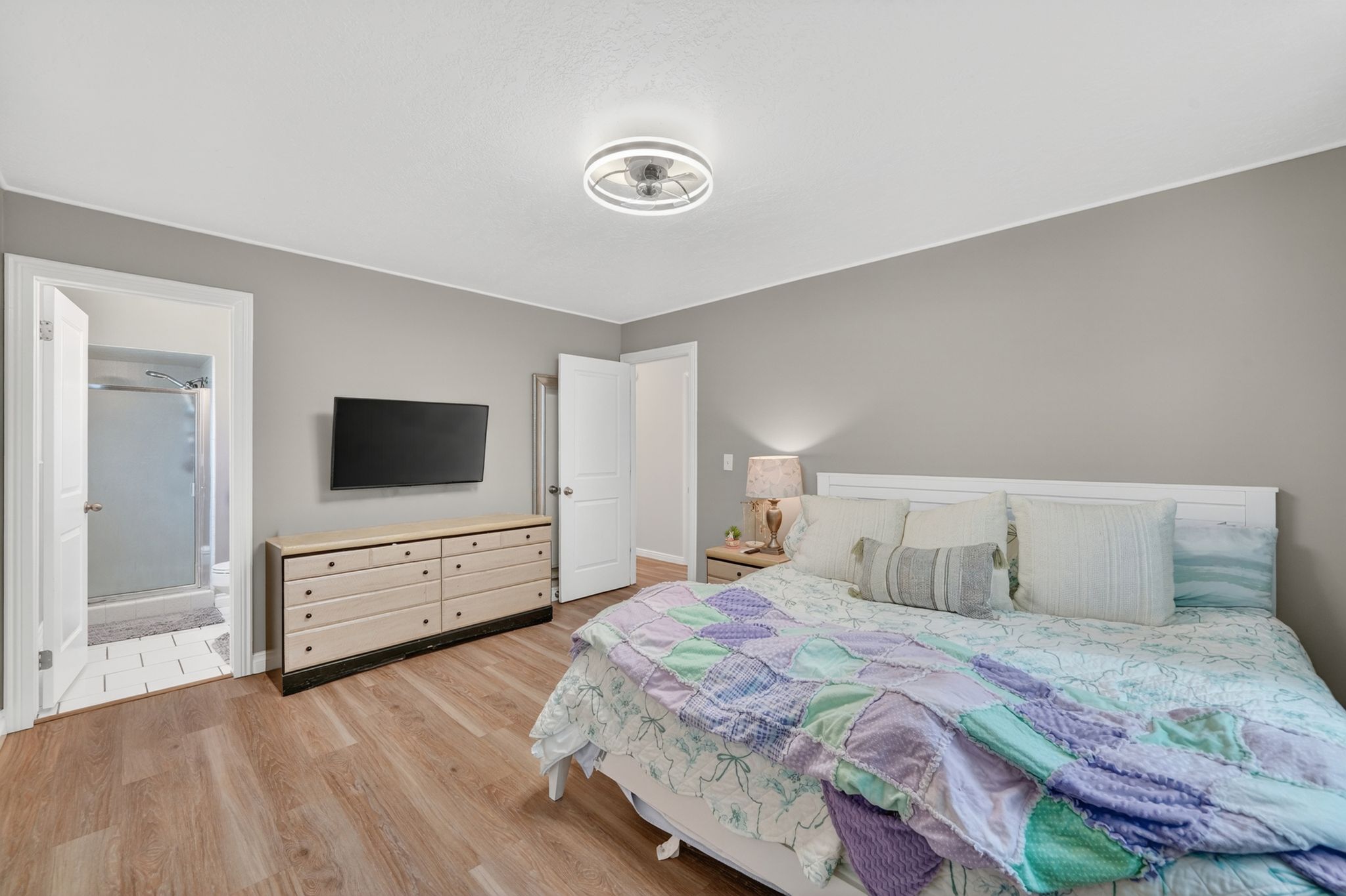 Bedroom featuring wood-finish flooring, light gray walls, and a modern ceiling fan with integrated lighting
