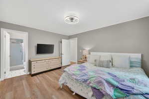 Bedroom featuring wood-finish flooring, light gray walls, and a modern ceiling fan with integrated lighting