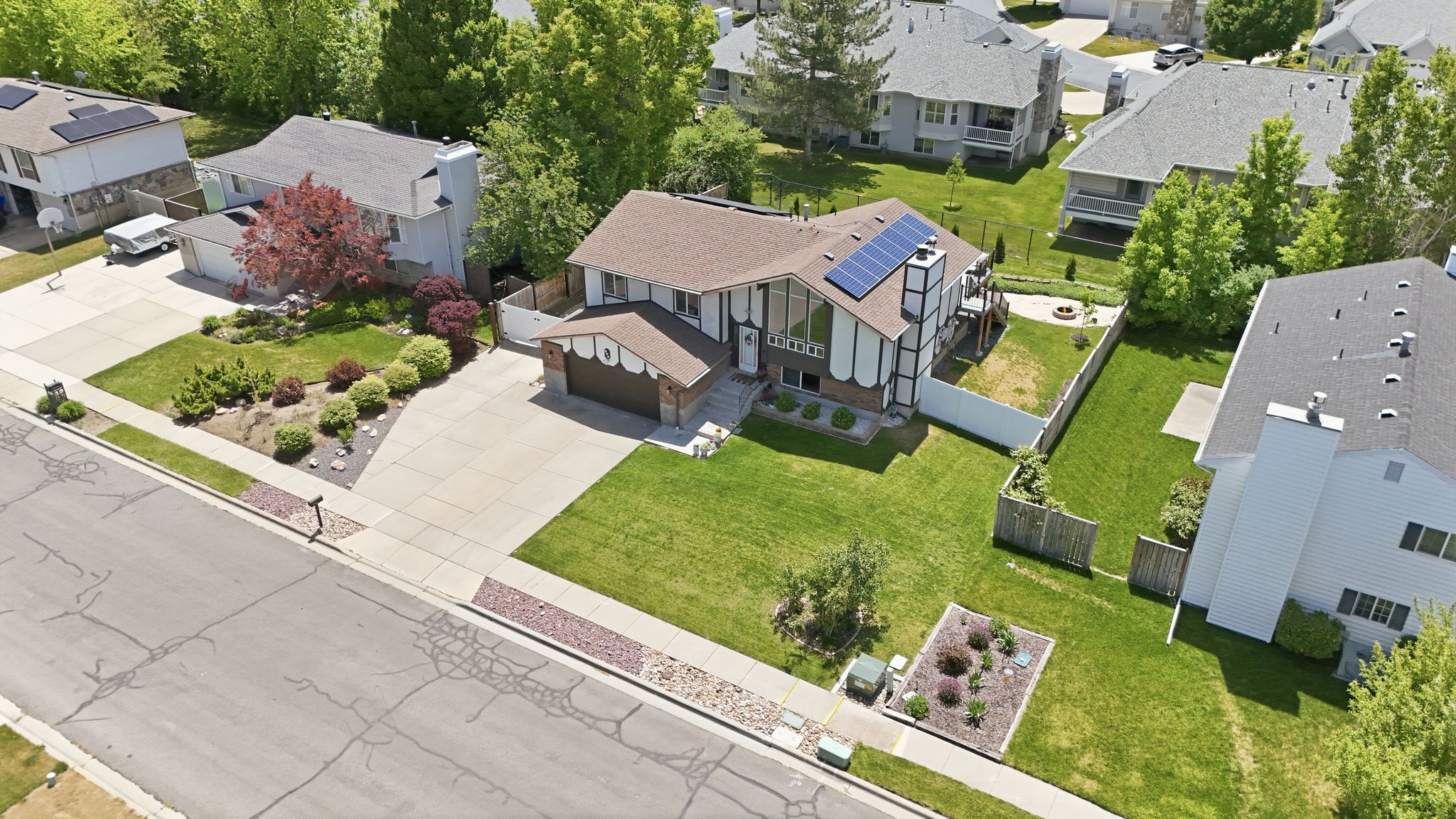 Split-level residence featuring a brown shingled roof with solar panels and a two-car garage