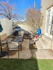 Concrete patio with direct access to a grassy area, featuring a built-in outdoor grilling station and a privacy fence