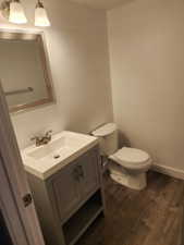 Powder room featuring a gray wood-finish vanity with an integrated sink, brushed nickel faucet, framed mirror, and wood-look flooring