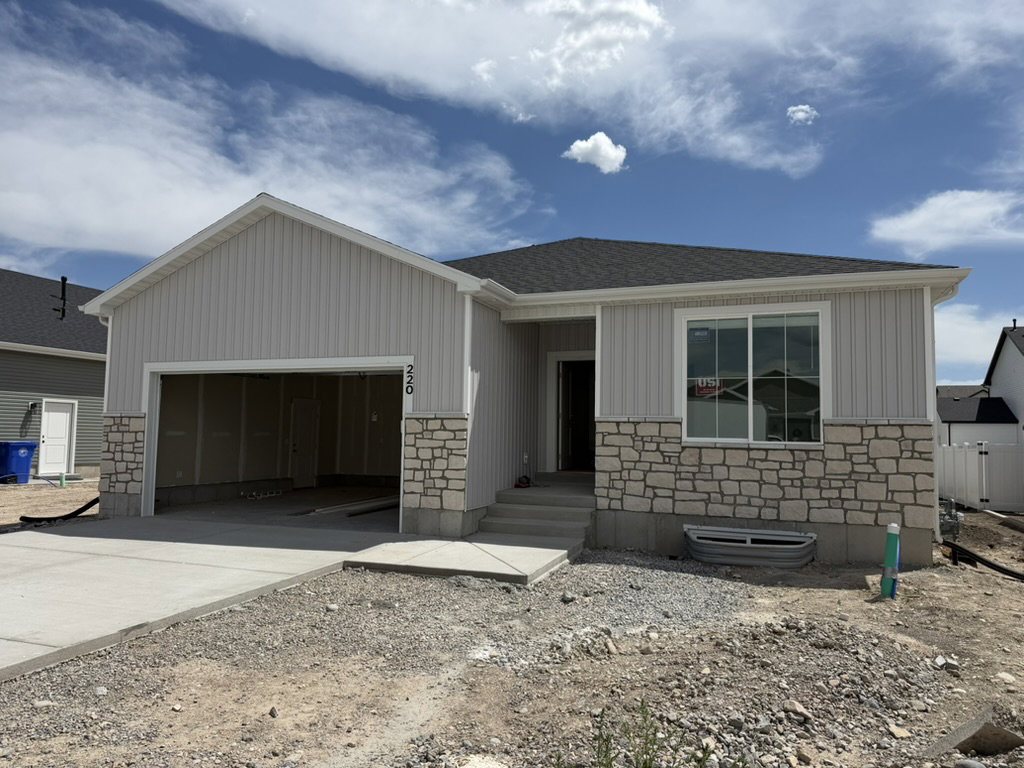 Single-story residence featuring light-toned vertical siding and stone veneer accents