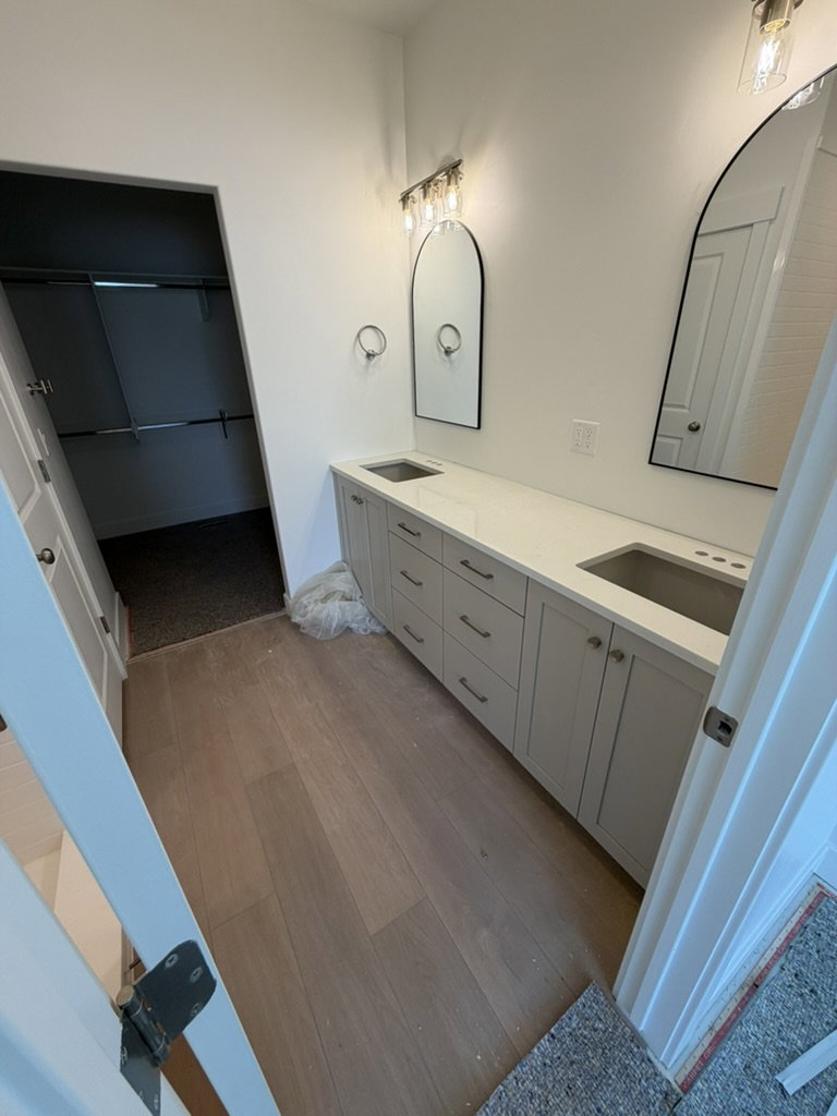 Bathroom vanity featuring dual under-mount sinks, light-toned cabinetry, and quartz countertops