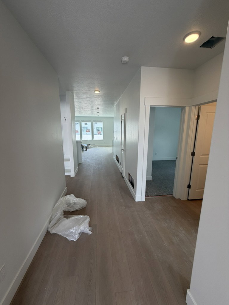Long hallway featuring light wood-finish flooring, recessed ceiling lighting, and crisp white baseboards