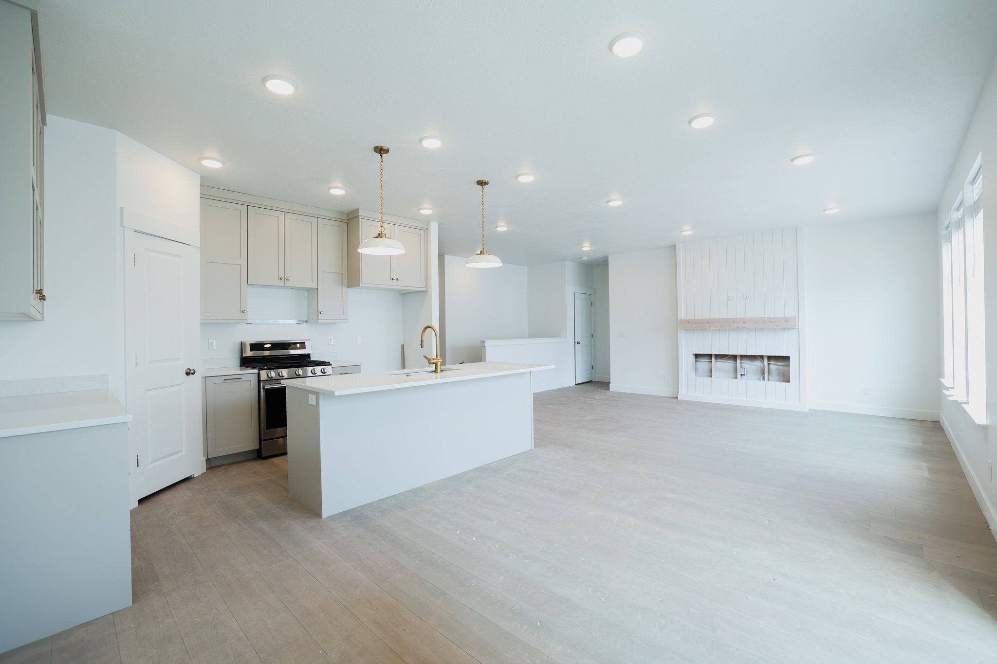 Open-concept living space featuring a modern kitchen with light cabinetry, a central island, and stainless steel appliances