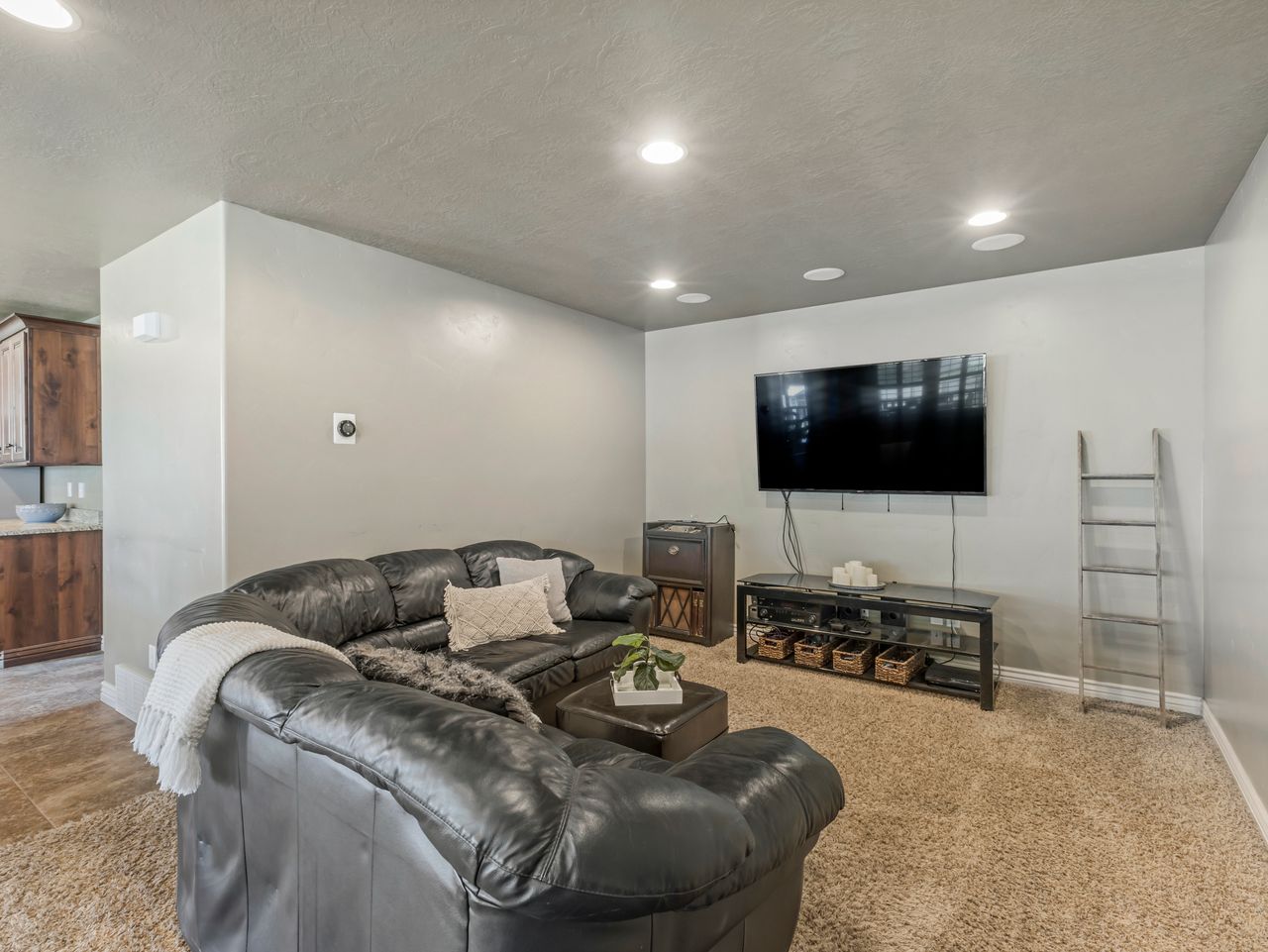 Recessed ceiling lighting illuminates a carpeted living area with light gray walls