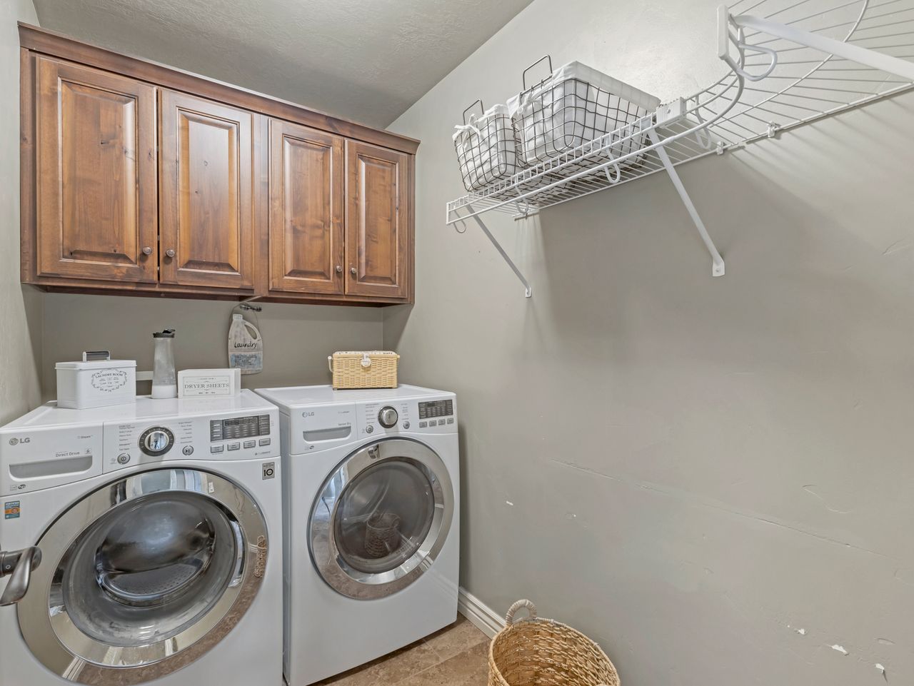 Dedicated laundry area featuring dark wood-finish cabinetry, wire shelving, and neutral wall tones