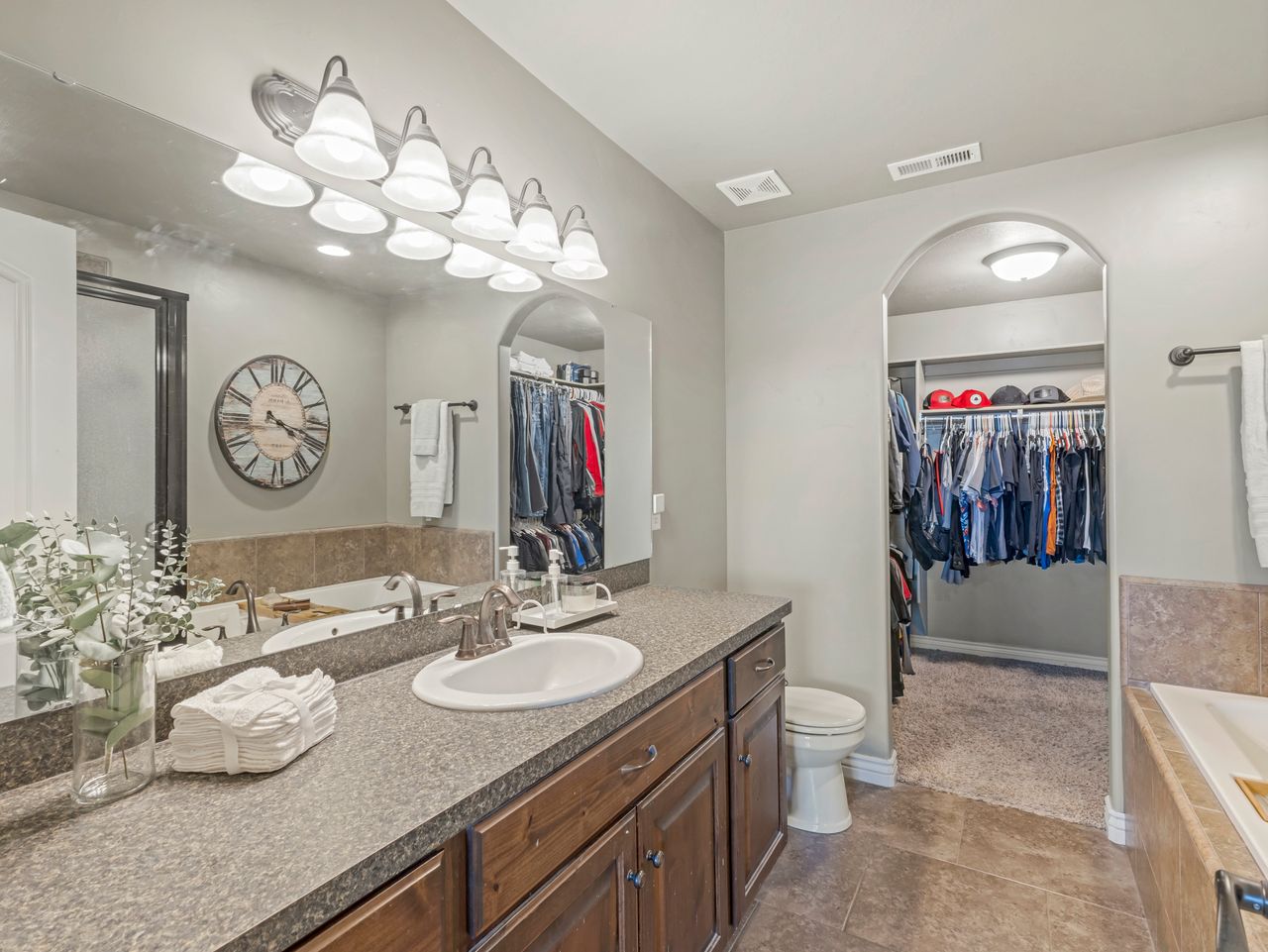 Bathroom vanity featuring dual sinks, wood-finish cabinetry, and a full-width mirror