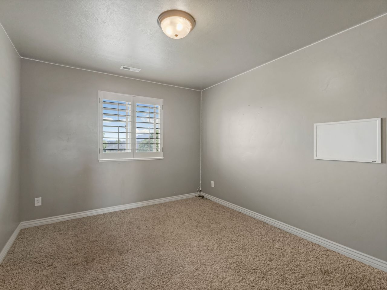 Neutral-toned room featuring a single window with white plantation shutters