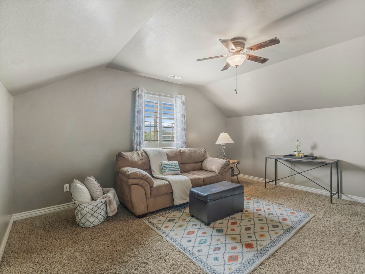 Carpeted room featuring a sloped ceiling and a ceiling fan with integrated lighting