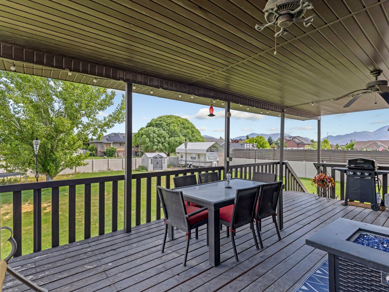 Covered outdoor deck featuring a dark wood-finish surface, a ceiling fan, recessed lighting, and a protective railing