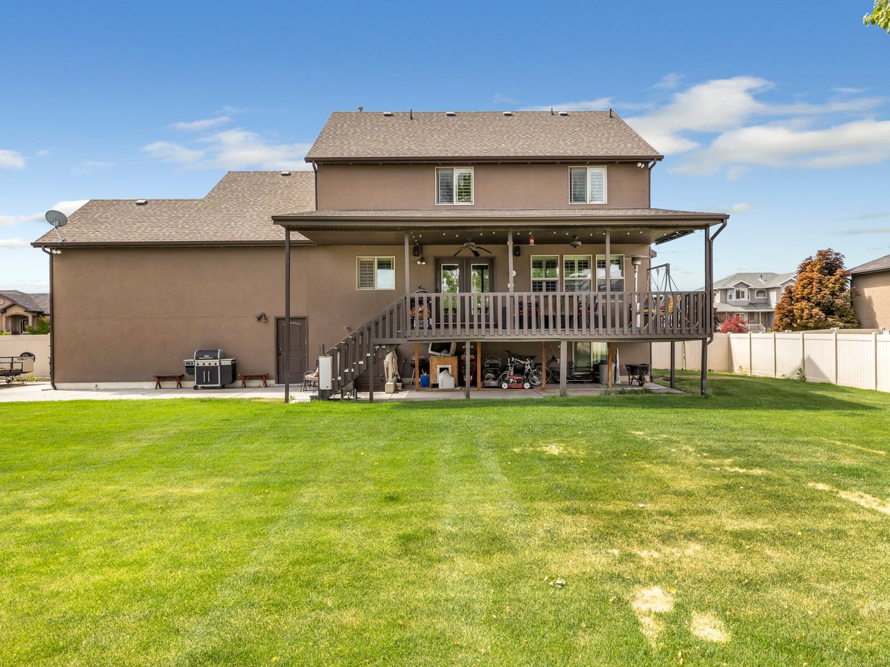 Expansive green lawn with a two-story stucco exterior and a covered deck