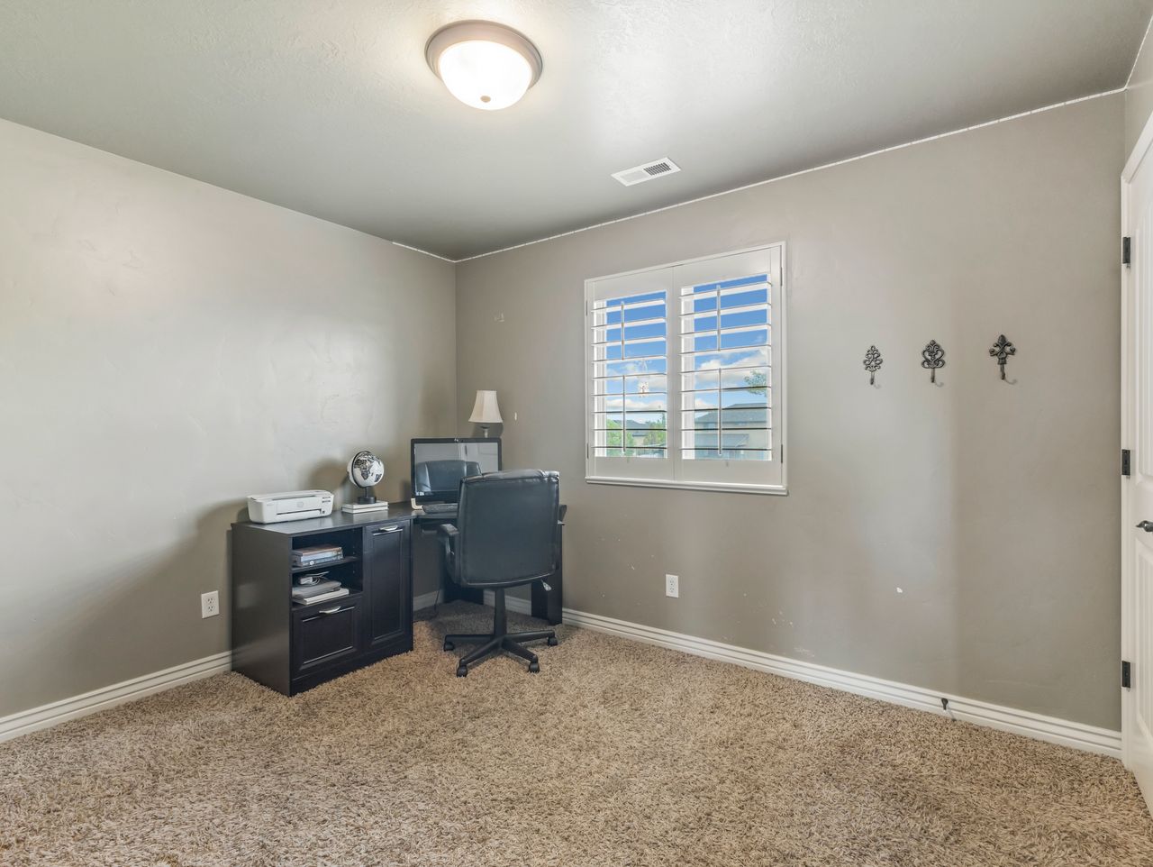 Light-filled room featuring a window with white plantation shutters, carpet flooring, baseboard molding, and a flush-mount ceiling light fixture