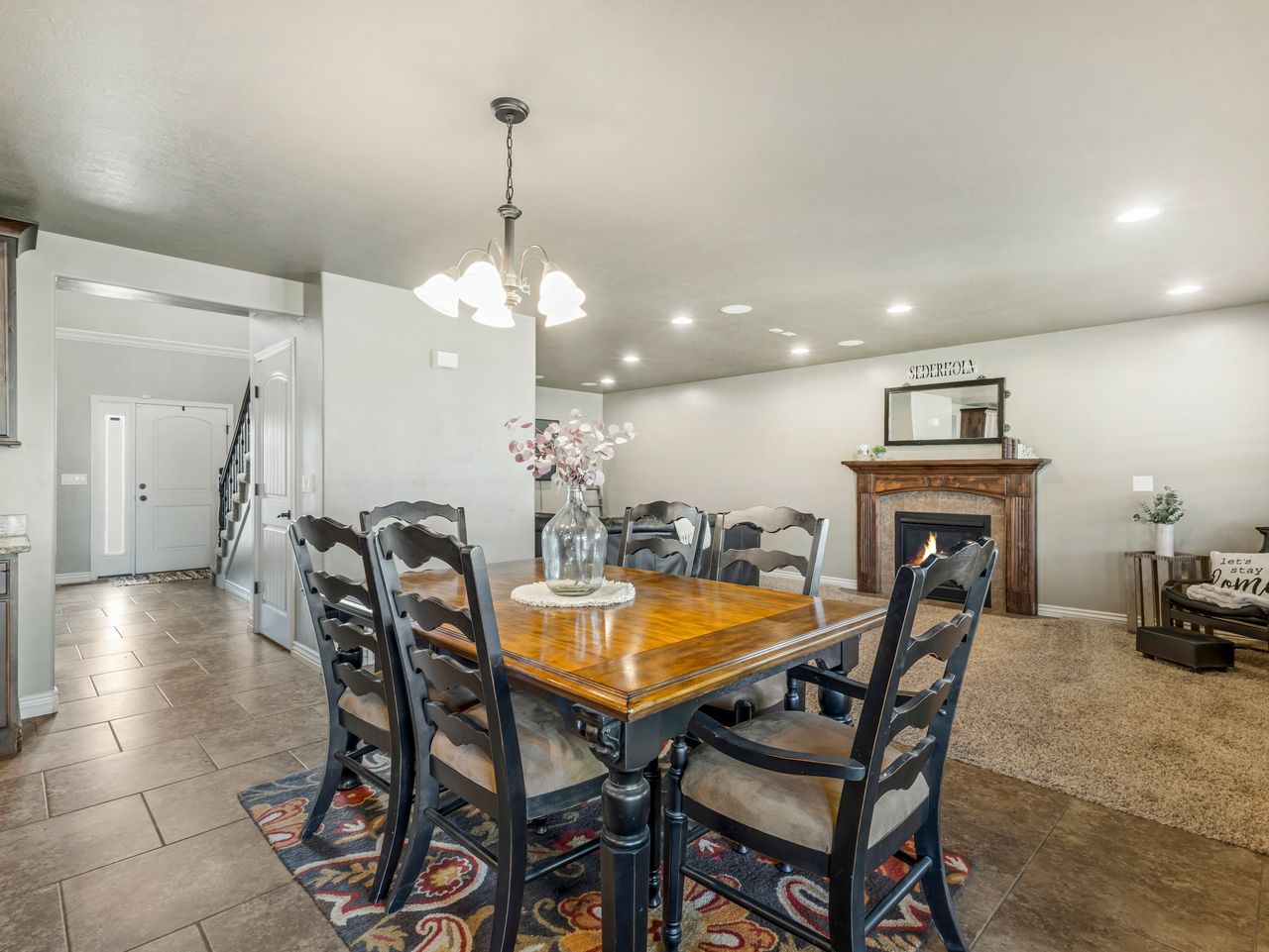 Open-concept dining area featuring a chandelier, tile flooring, and direct access to the entry