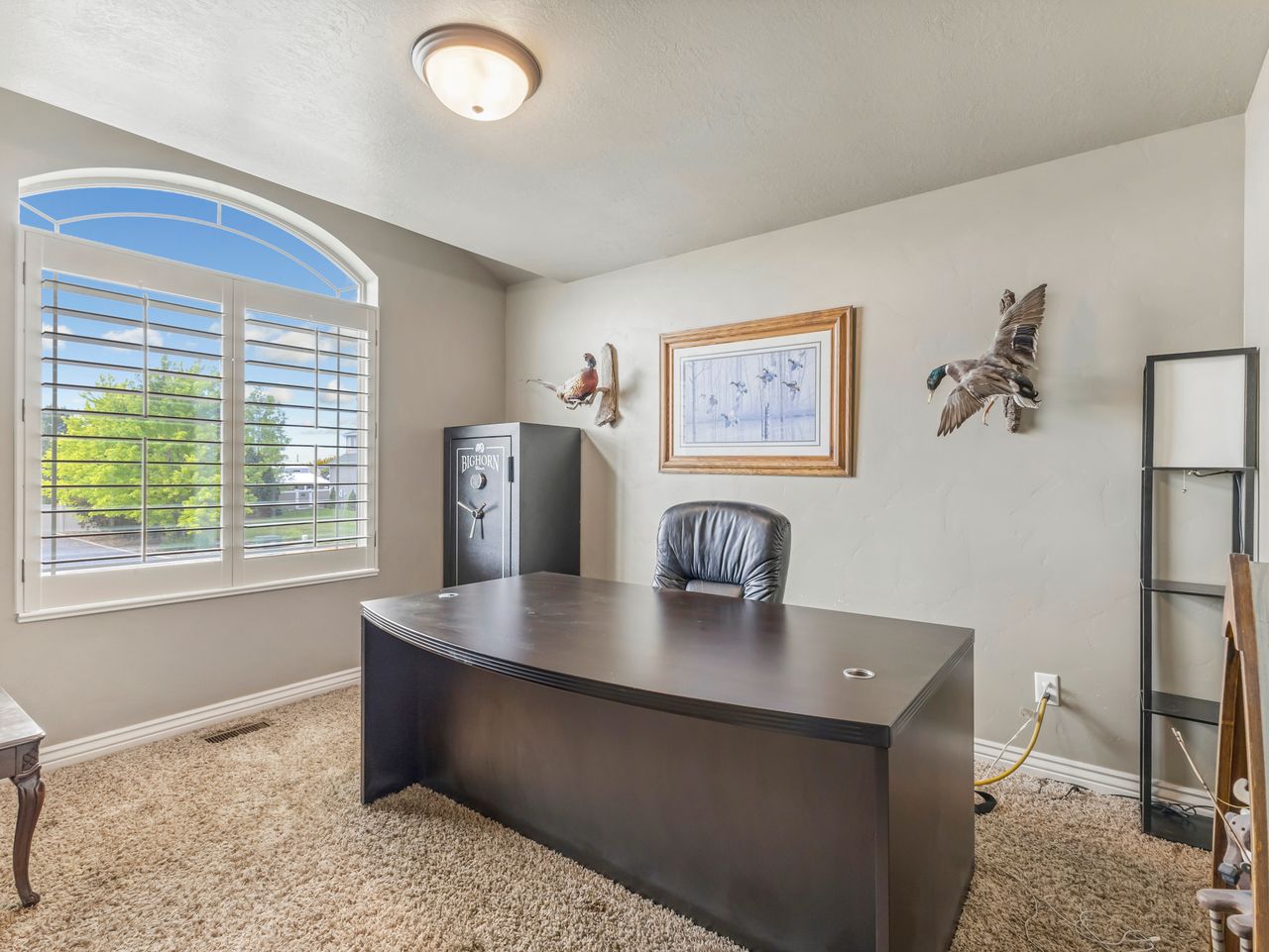 Room featuring an arched window with plantation shutters, neutral wall color, and carpet flooring