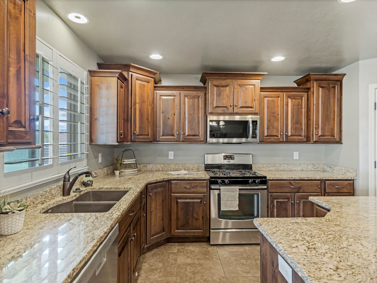 Kitchen featuring wood cabinetry, light-toned granite countertops, and stainless steel appliances