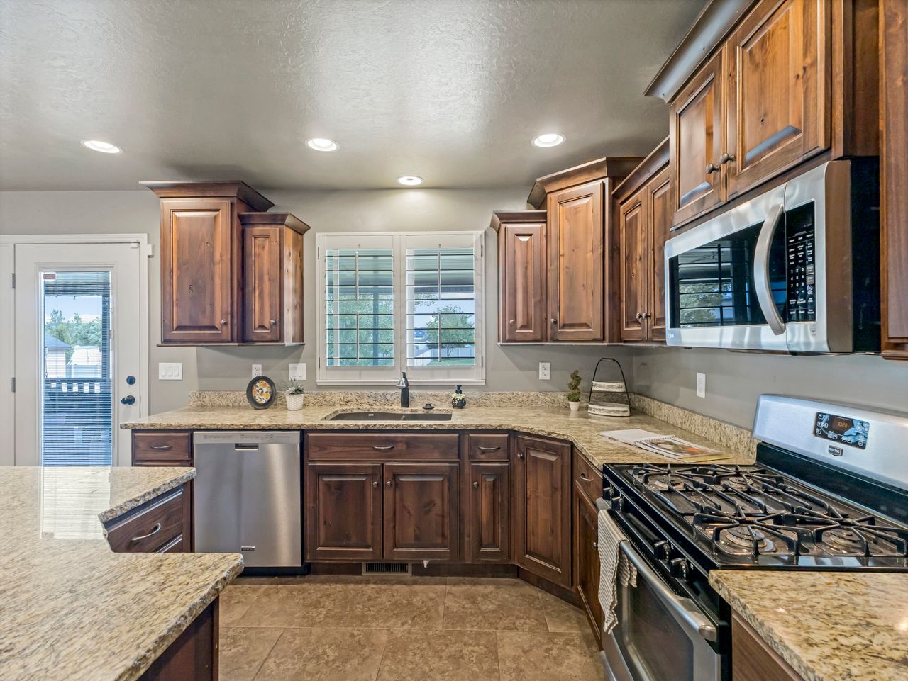 Kitchen featuring wood cabinetry, granite countertops, stainless steel appliances, and recessed lighting