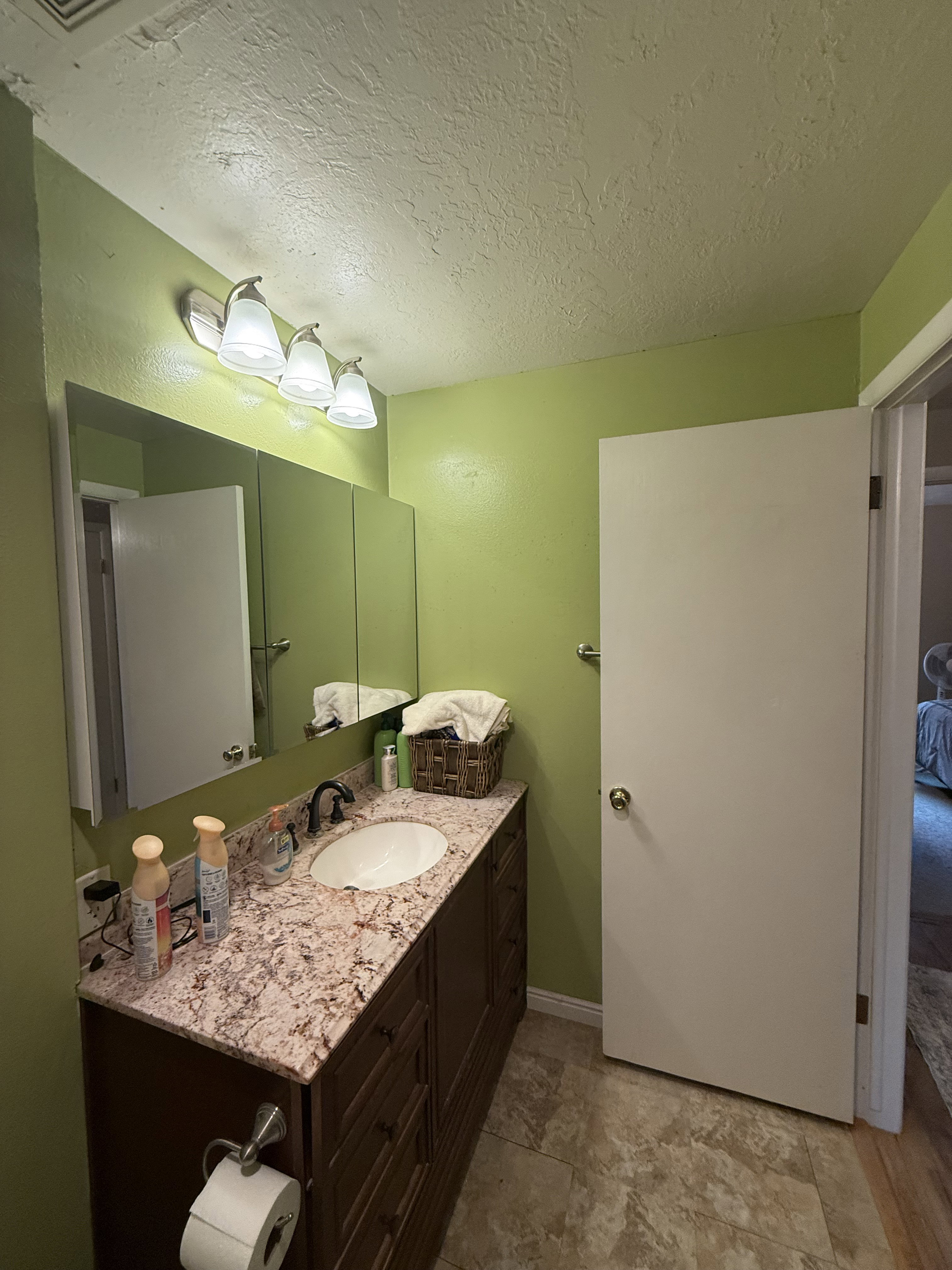 Bathroom vanity featuring a built-in oval sink, granite-style countertop, and dark wood-finish cabinetry