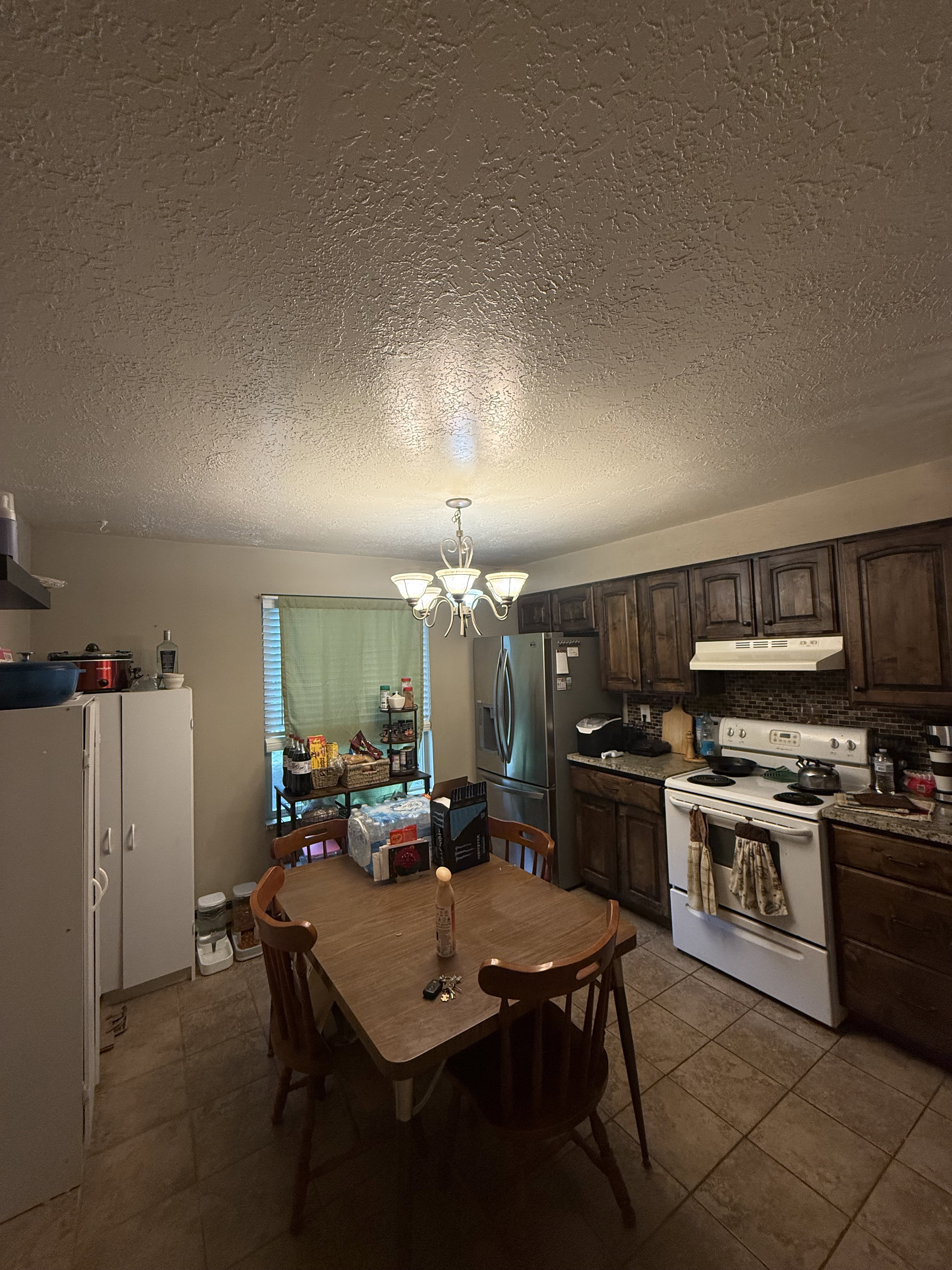 Functional kitchen space featuring dark wood cabinetry, a white electric range, and a stainless steel refrigerator