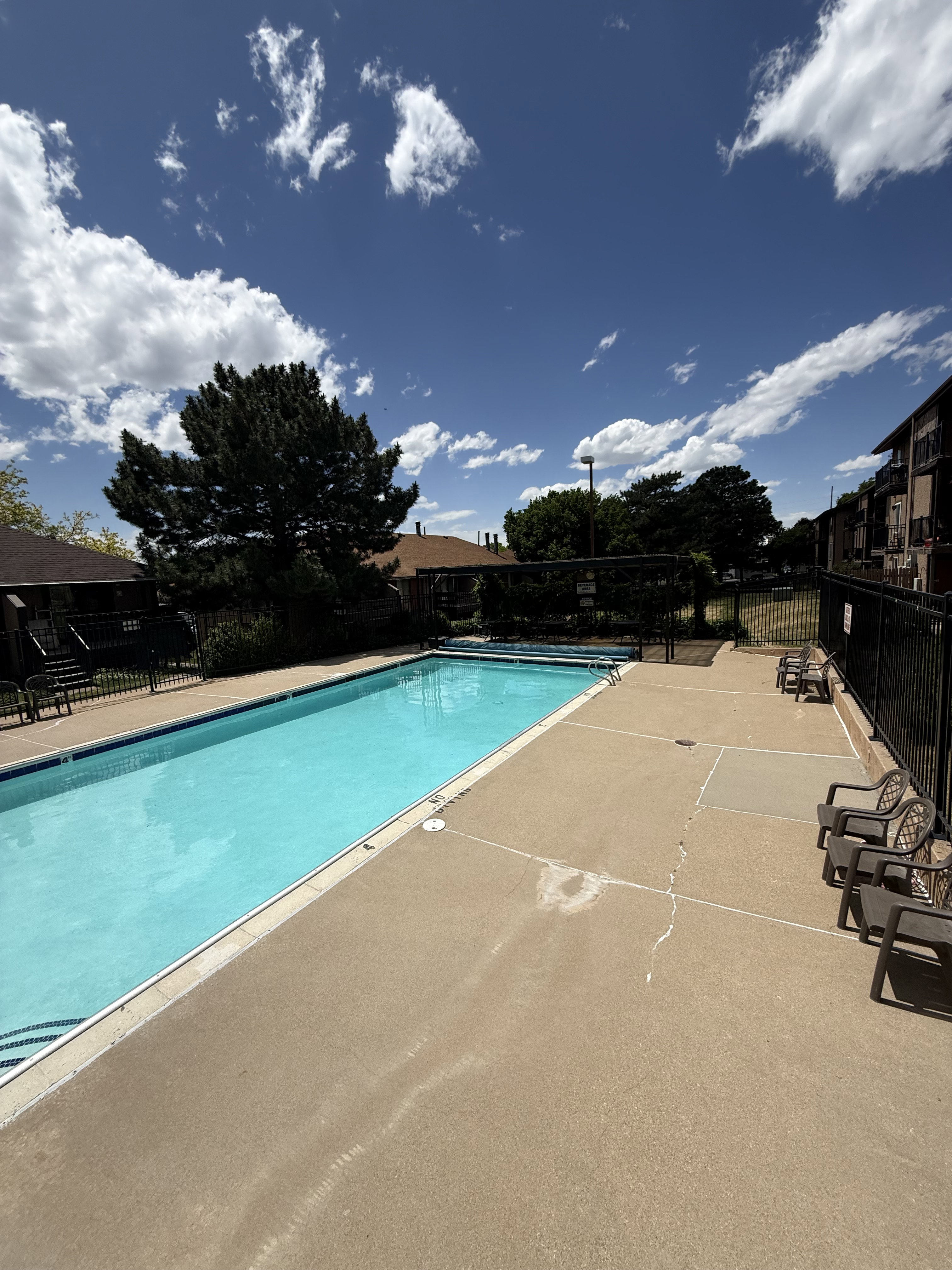 Outdoor swimming pool with concrete decking and surrounding black metal fencing