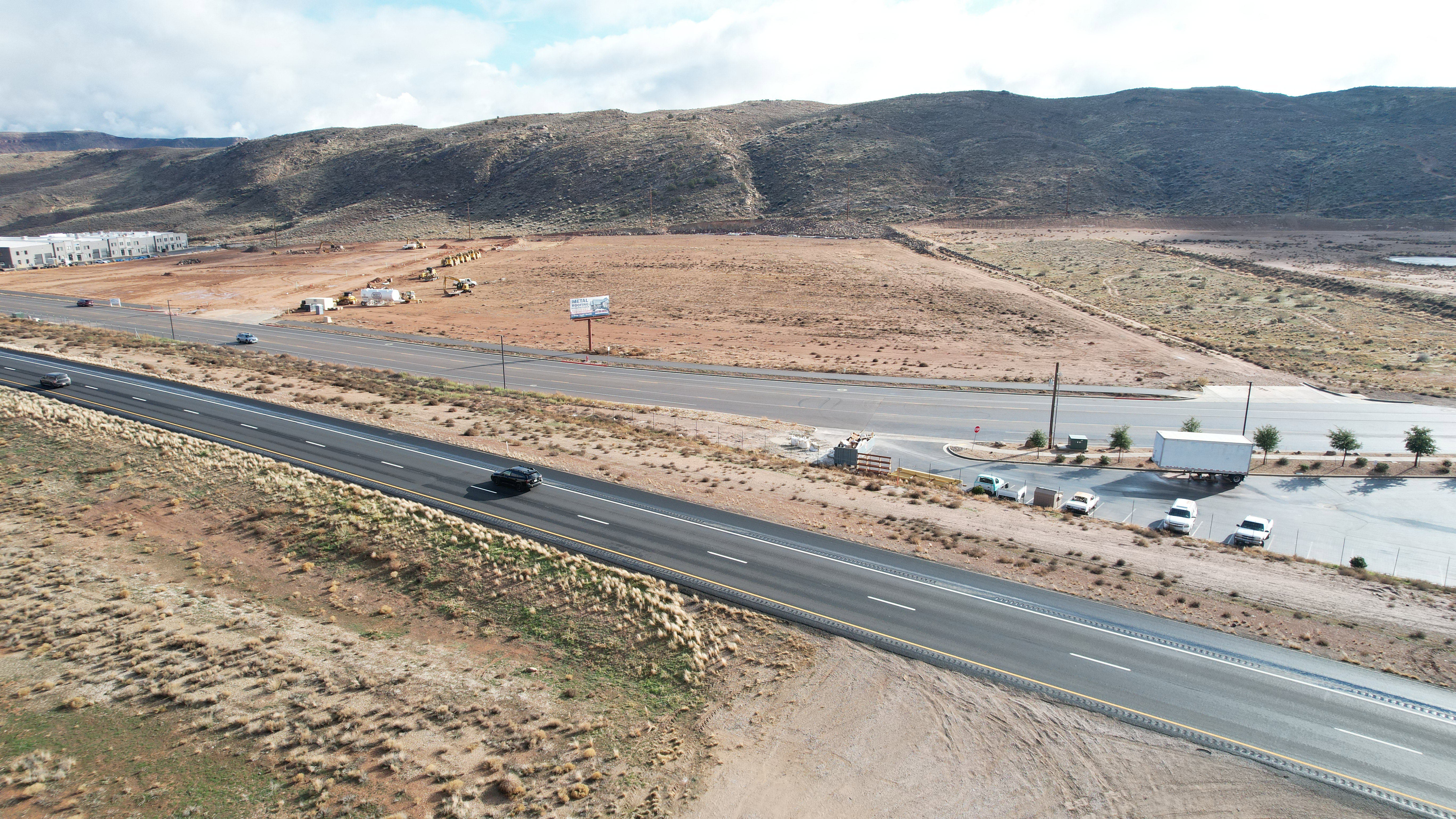 Highway frontage with desert landscape and distant commercial buildings
