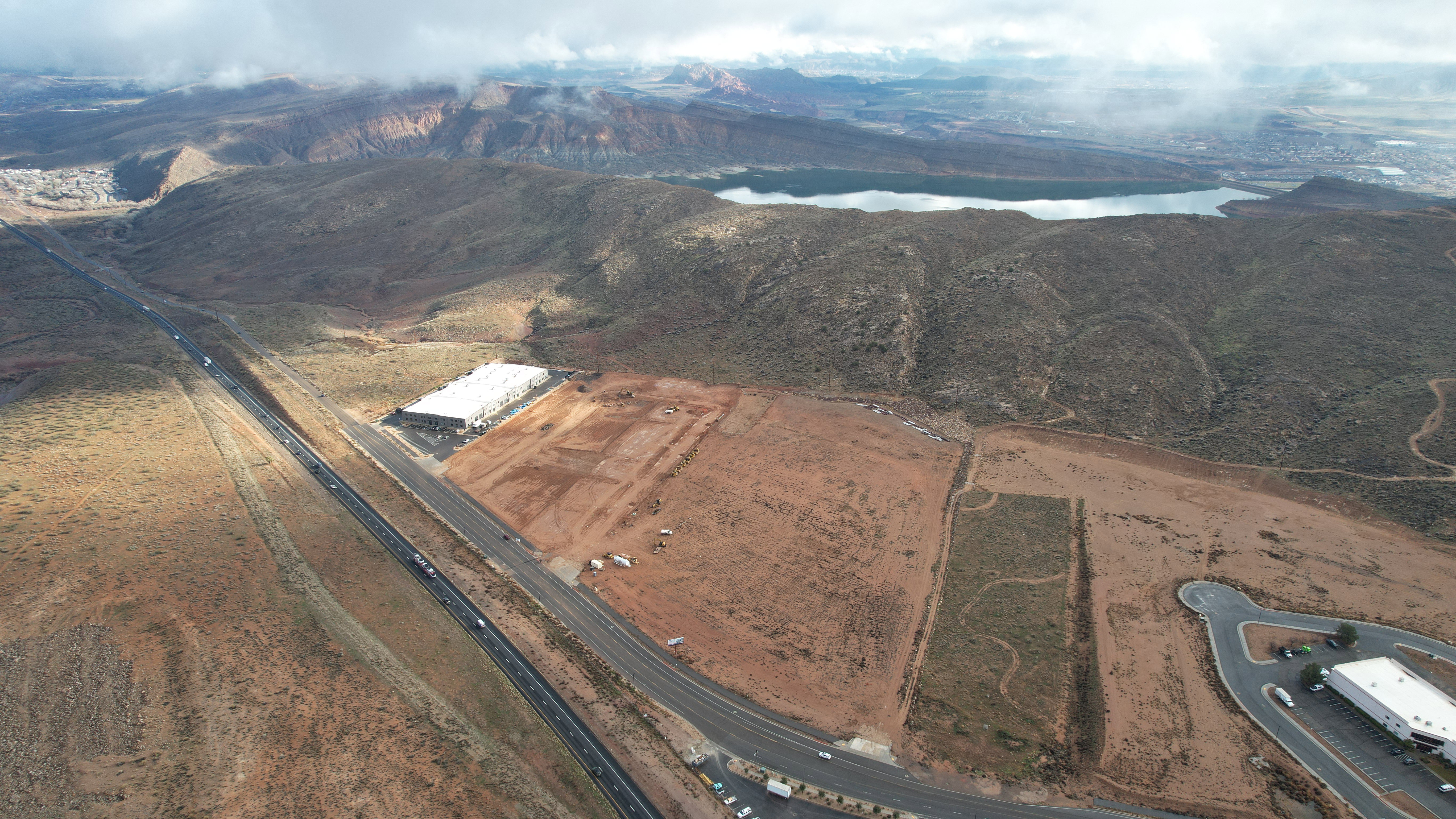 Expansive aerial perspective showcasing a commercial building with a white roof, situated alongside a multi-lane highway