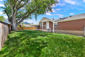 Spacious backyard with a mature shade tree, manicured lawn, and wood privacy fencing