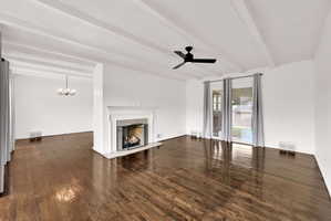 Living area featuring rich wood-finish flooring and a white mantel fireplace with a dark screen