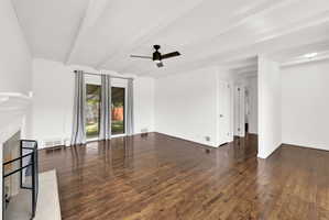 Spacious living area featuring rich wood-finish flooring and a white beamed ceiling