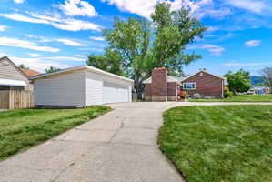 Expansive concrete driveway leading to a detached two-car garage with white siding