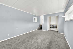 Spacious room featuring light blue walls, grey plush carpeting, and white trim