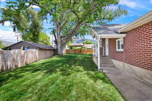 Expansive green space featuring a mature shade tree, a wood privacy fence, and a detached garage
