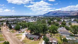 Expansive aerial perspective showcasing a neighborhood with mature trees and mountain backdrops