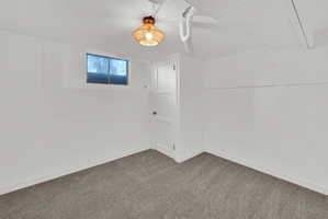Carpeted interior space featuring a single window, white paneled door, and a woven pendant light fixture
