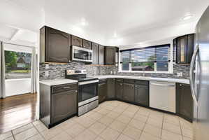 Kitchen featuring dark wood cabinetry, a mosaic tile backsplash, white countertops, and recessed lighting