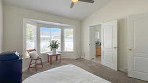 Vaulted ceiling bedroom featuring a bay window, carpet flooring, a ceiling fan, and a white paneled door