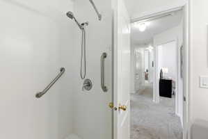 Walk-in shower with integrated grab bars, handheld showerhead, and wall-mounted controls