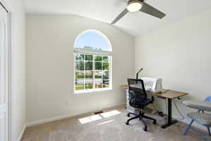 Arch-top window with grid pattern, vaulted ceiling, and ceiling fan