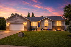 AI Enhanced Twilight.  Ranch-style residence featuring a prominent two-car garage with overhead lighting