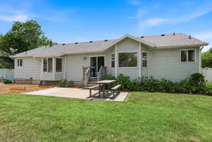 Expansive backyard featuring a concrete patio, a raised deck with stairs, and a sliding glass door