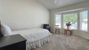 Spacious room featuring vaulted ceilings, bay windows with blinds, and soft grey carpet